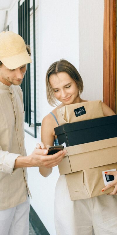 A man and woman engaged in a home delivery package exchange, smiling.